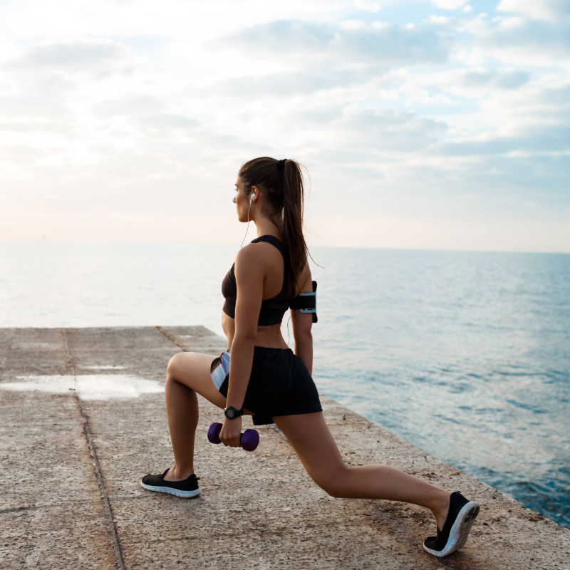 Jovem atleta executando agachamento com pesos, focada no fortalecimento das pernas e glúteos